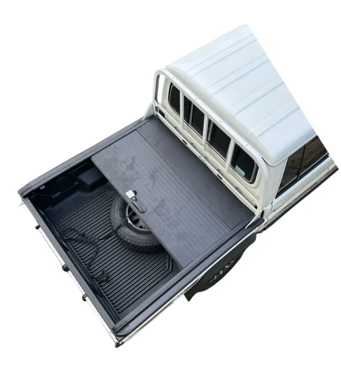 Vista superior de la tapa de aluminio Land Cruiser parcialmente abierta, mostrando el área de la llanta de repuesto