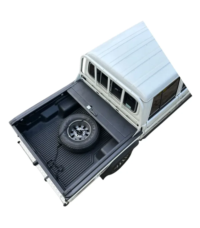 Vista superior de la tapa de cama Land Cruiser abierta, mostrando el acceso completo a la caja y la llanta de repuesto
